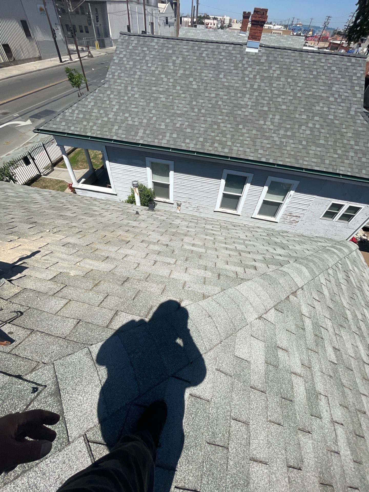 Shingle roof after restoration treatment next to an untreated neighboring roof
