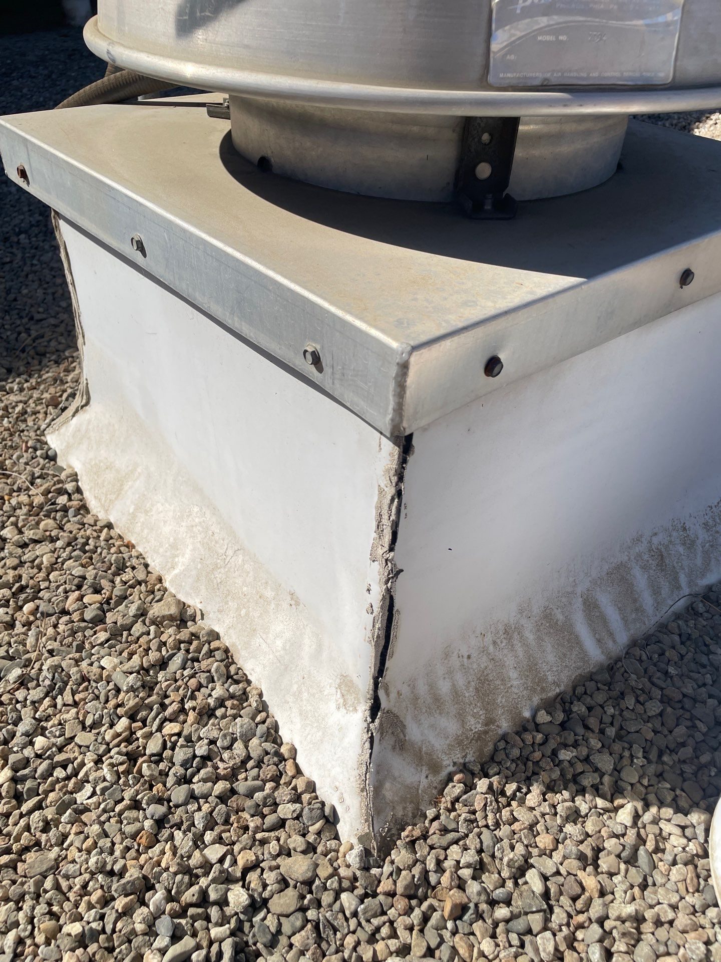 Cracked seam on the metal corner of a rooftop vent curb