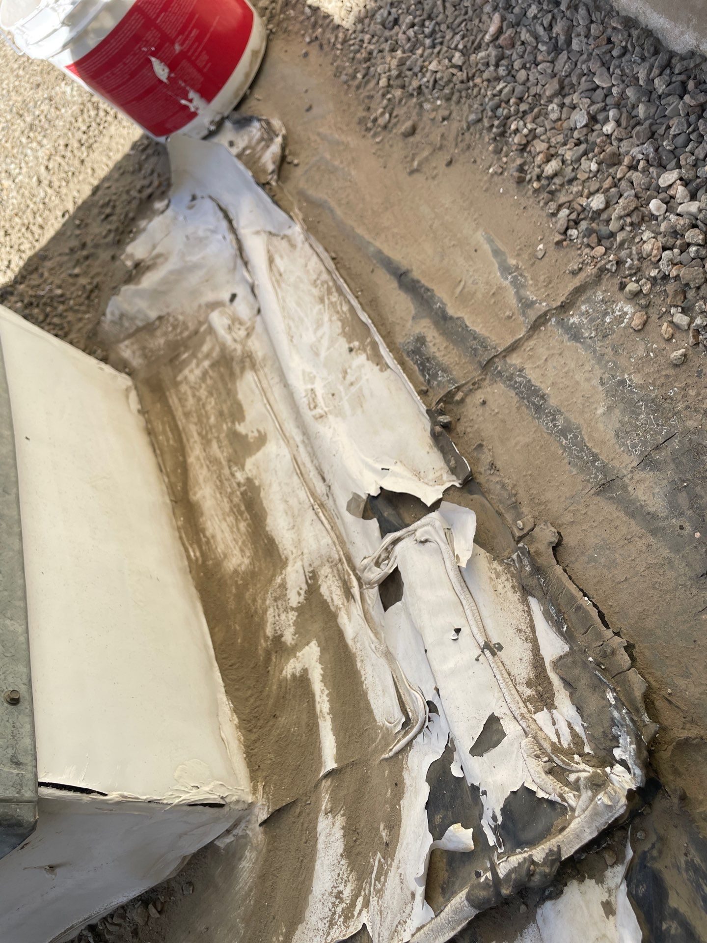 Bucket of sealant or coating material applied along a roof edge