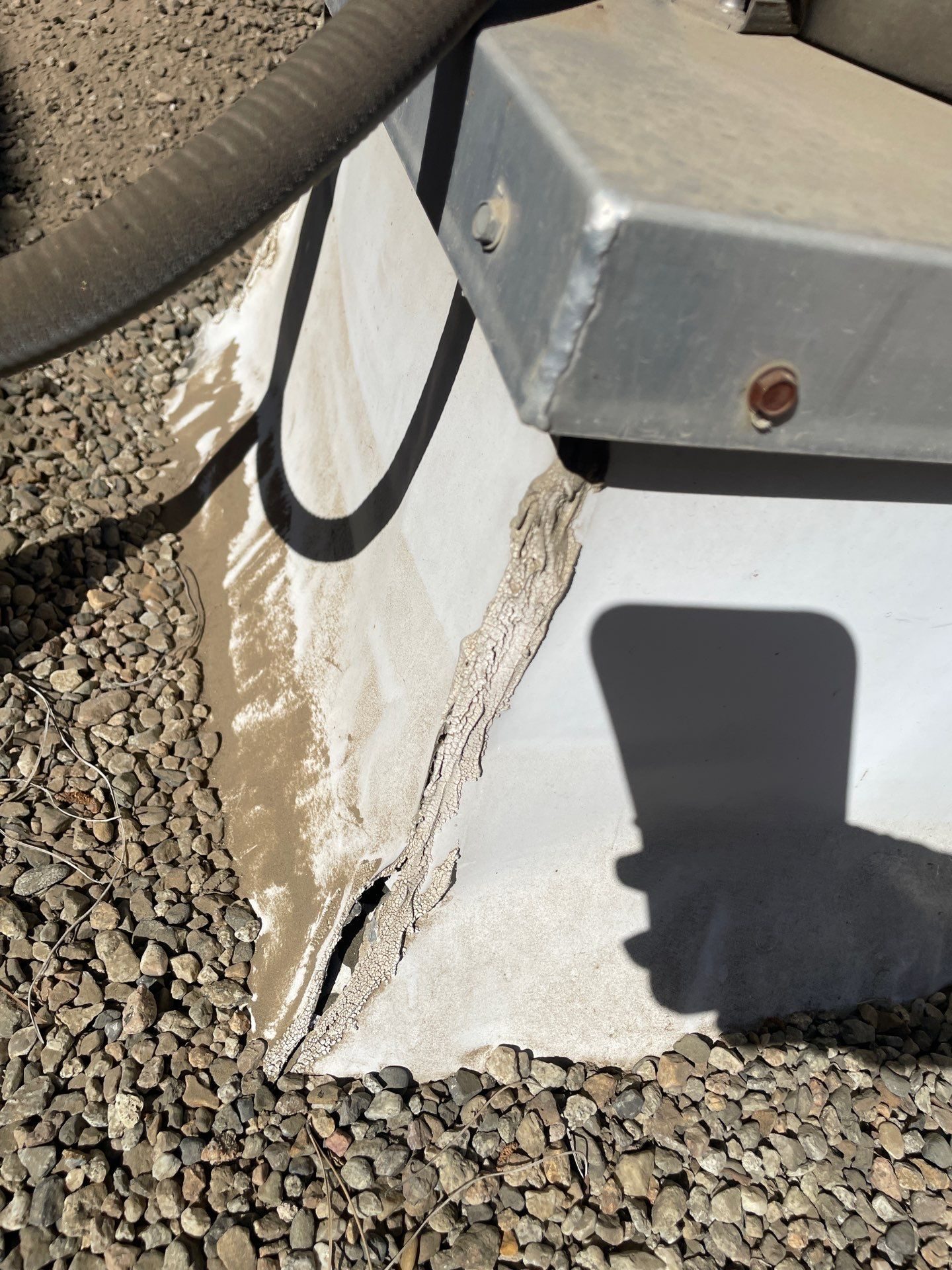 Torn membrane flashing at the corner of a rooftop equipment unit