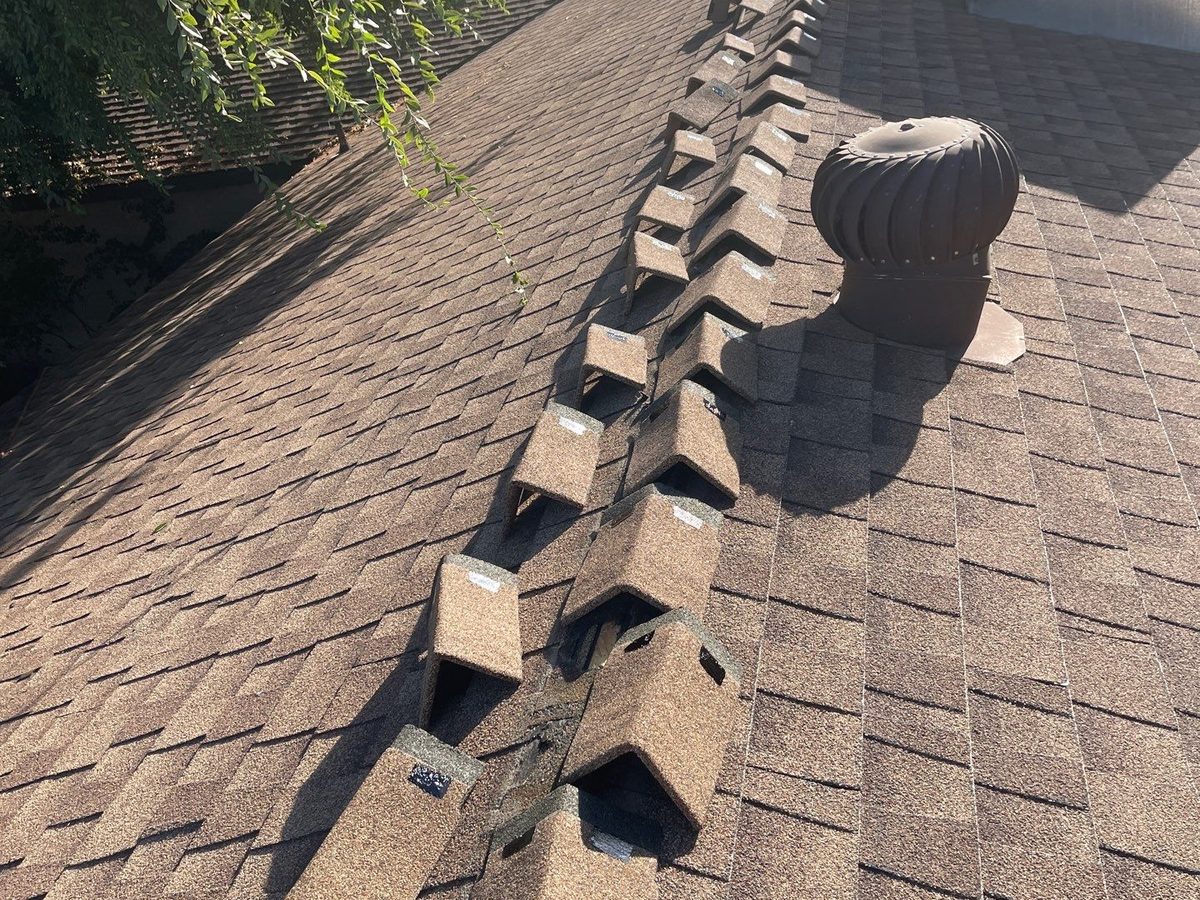 New ridge cap shingles laid out along the hip of a Clovis roof before installation, next to a turbine vent